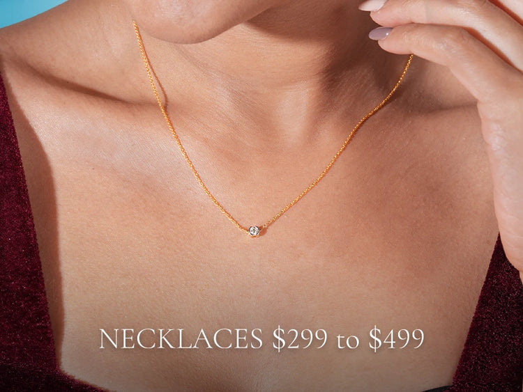 Model wearing a minimalist gold necklace with a solitaire diamond pendant, showcasing the $299–$499 collection by Vairam.